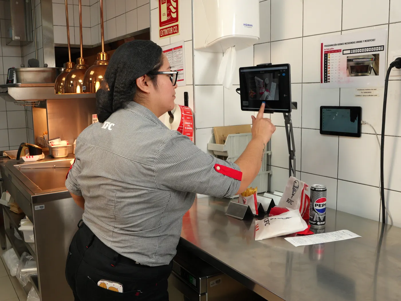 Una empleada de KFC enseña un pedido a Bronze Tracker en la mesa de salida de la cocina